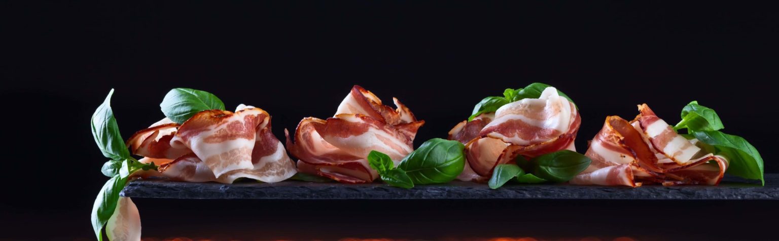 Folds of Creekside Farm bacon with fresh basil on slate