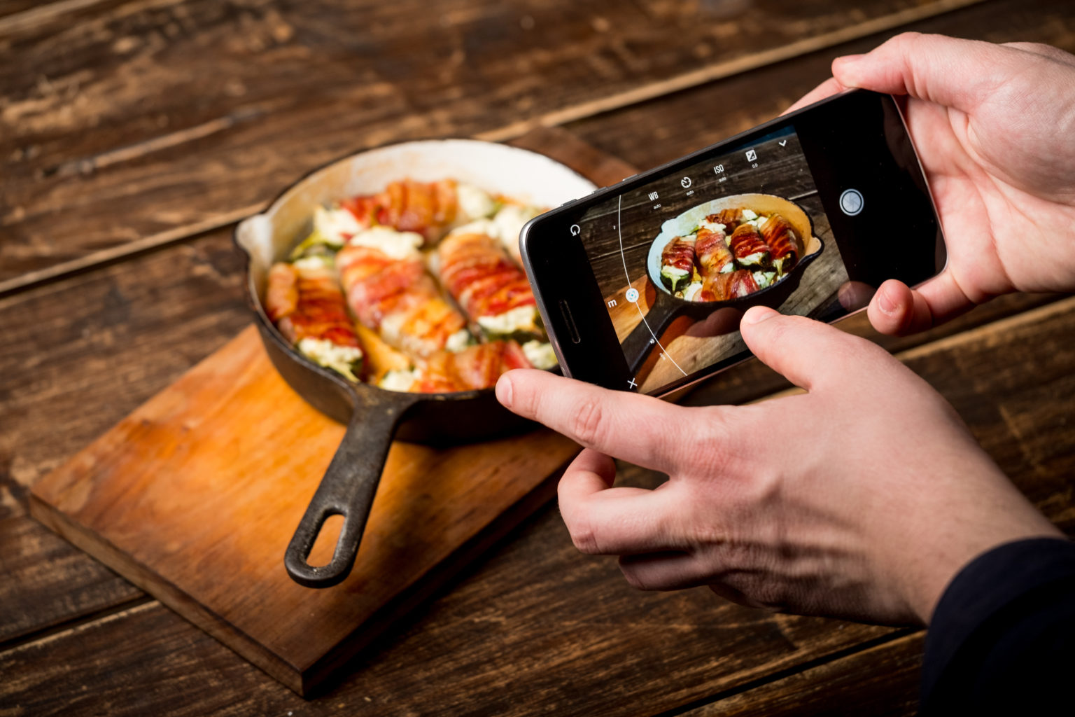 Photographing a pan of bacon-wrapped rolls on a wooden board