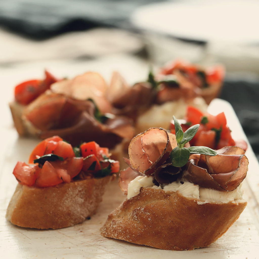 Toasted crostini topped with cured meat
