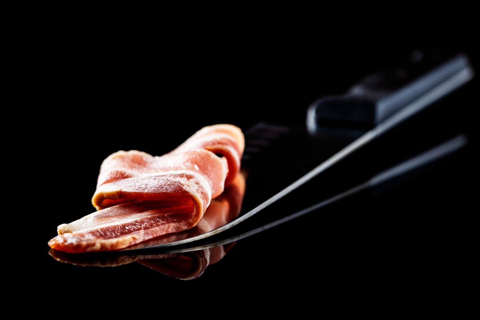 Folded rashers of bacon on a carving fork